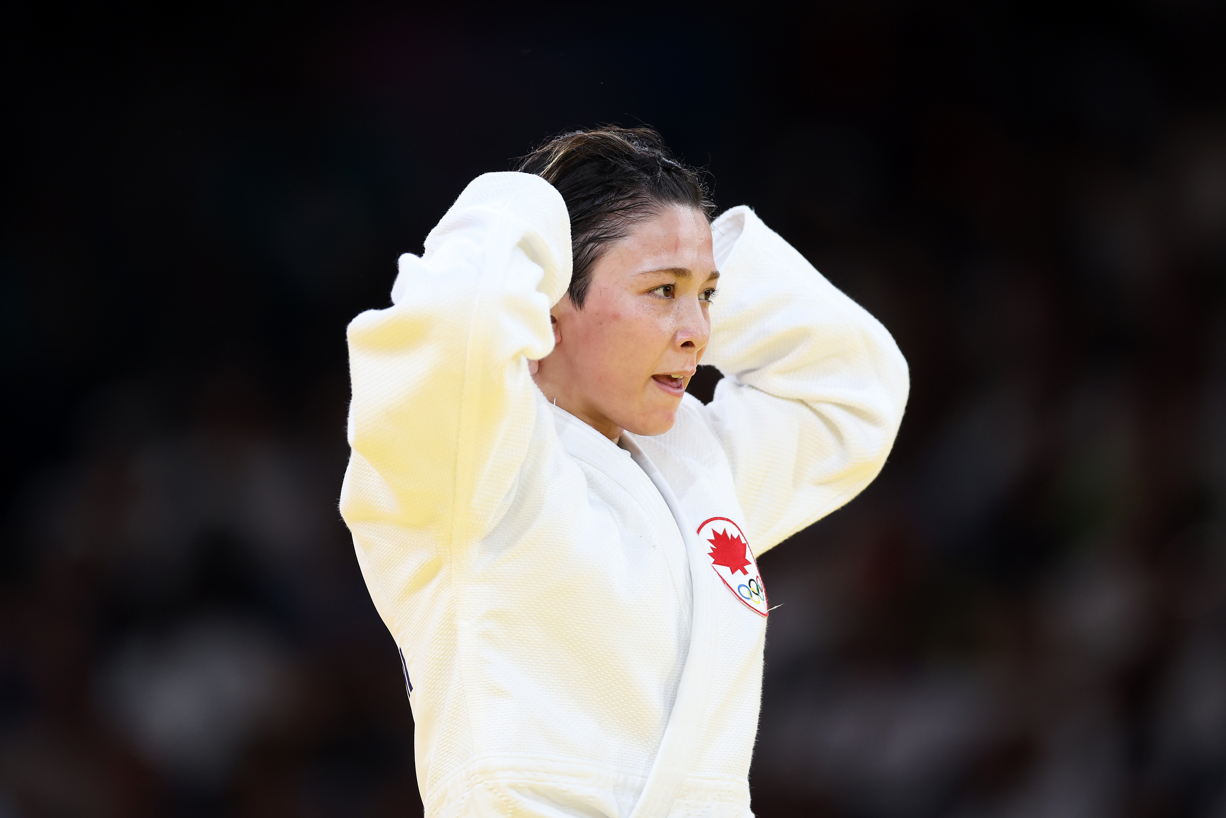 A person wearing a judo uniform appears to be focused and adjusting their hair, possibly preparing for a match