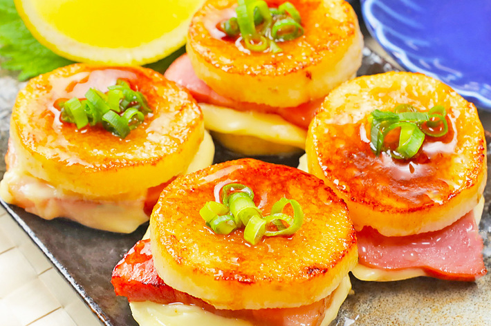 皿に盛られた4つのポテトとチーズ、ベーコンを使った料理。ネギがトッピングされ、美しく盛り付けられています。