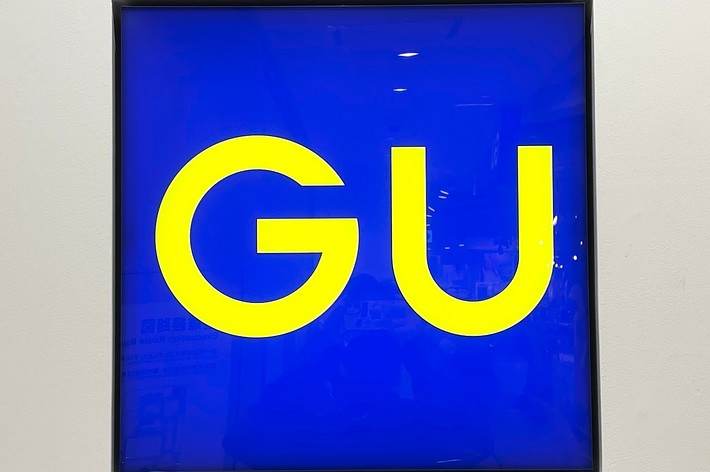 A wall sign displaying the letters ‘GU’ set against a blue background