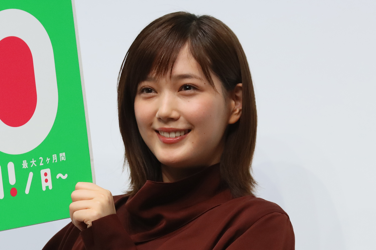 杉咲花がキャンペーンのポスターを持って笑顔で写っている。