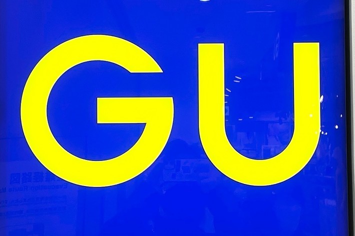 Square sign with the letters &ldquo;GU&rdquo; in bold yellow font on a deep blue background