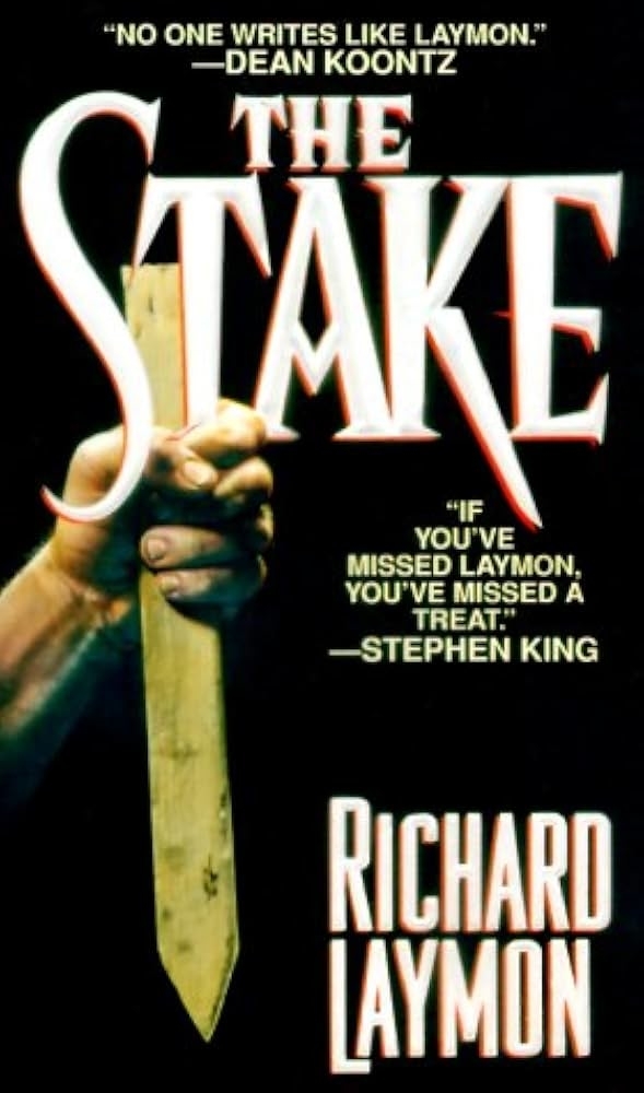 Cover of the book "The Stake" by Richard Laymon. Features endorsements by Dean Koontz and Stephen King and an image of a hand holding a wooden stake