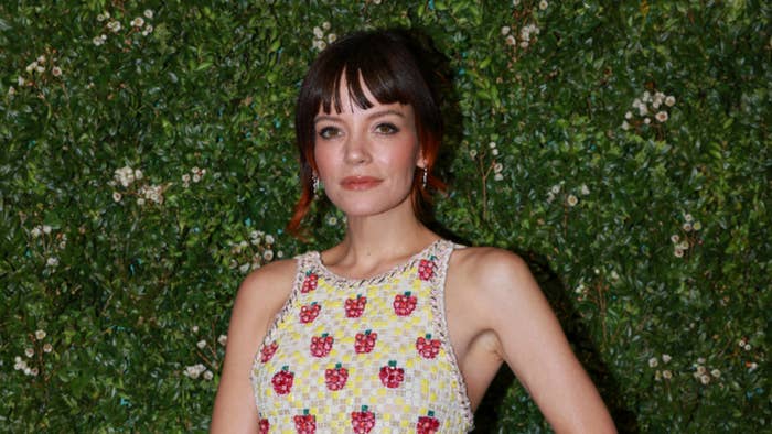 Lily Allen poses in a sleeveless, floral-patterned dress against a backdrop of greenery