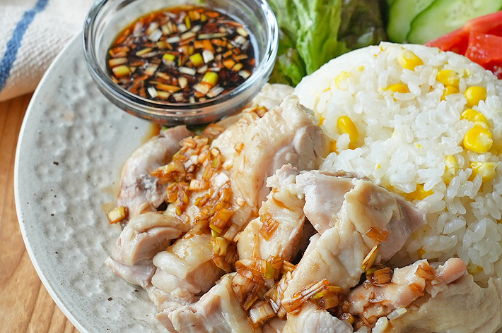 ご飯、鶏肉、野菜（レタス、キュウリ、トマト）とタレが盛り付けられたお皿。