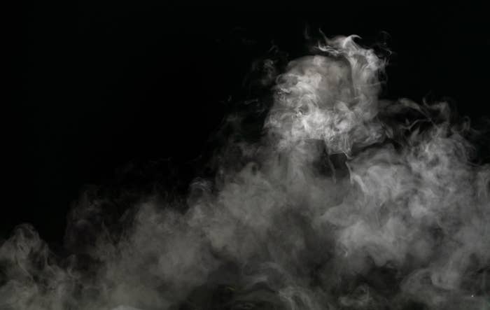 Dense smoke or fog swirling against a dark background, partially obscuring whatever lies behind it