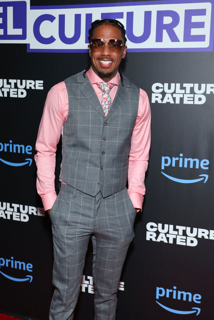 Nick Cannon is on the red carpet wearing a plaid vest suit and a pastel-colored shirt with a floral tie at a "Culture Rated" Prime event