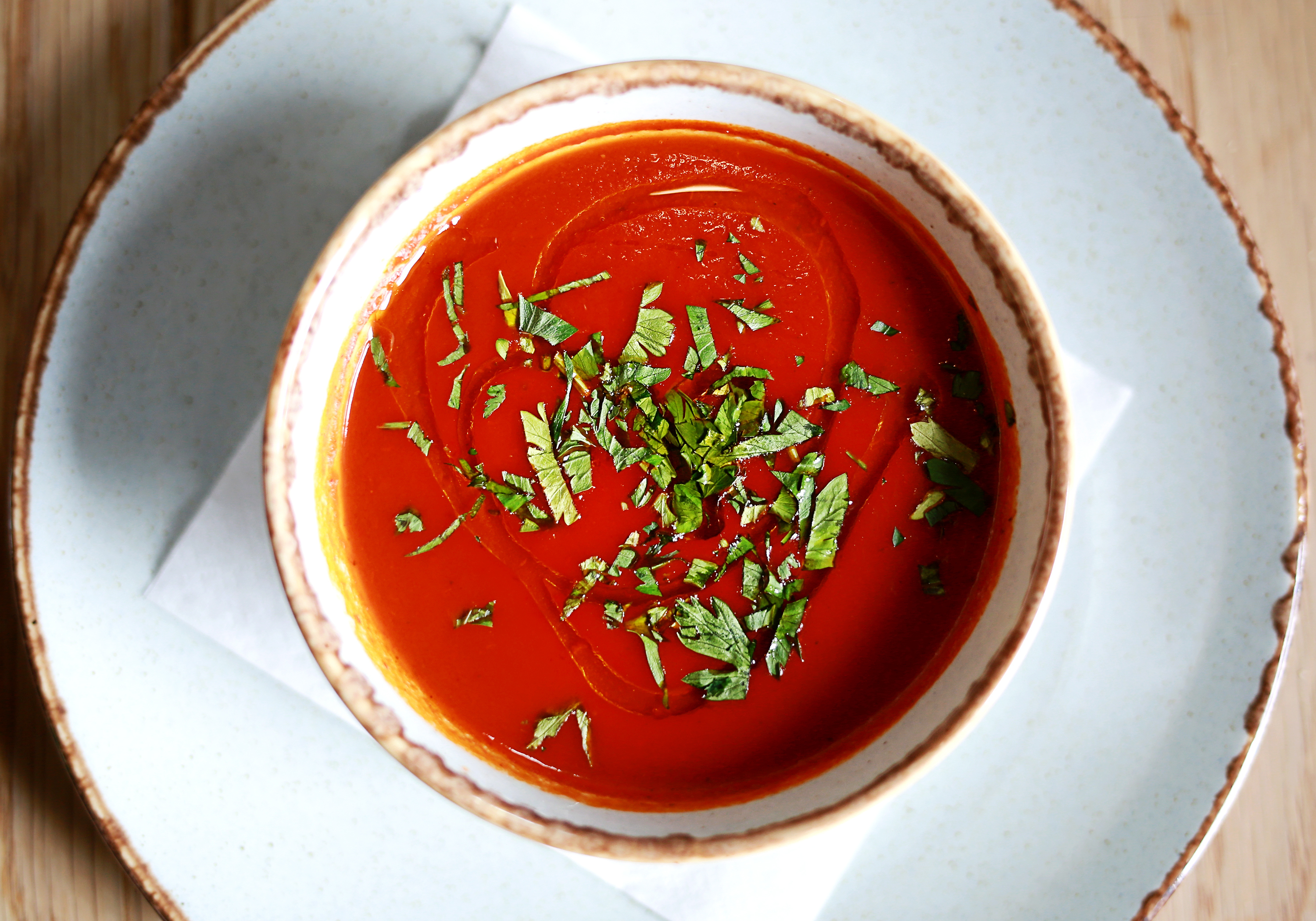 A bowl of tomato soup garnished with chopped fresh herbs