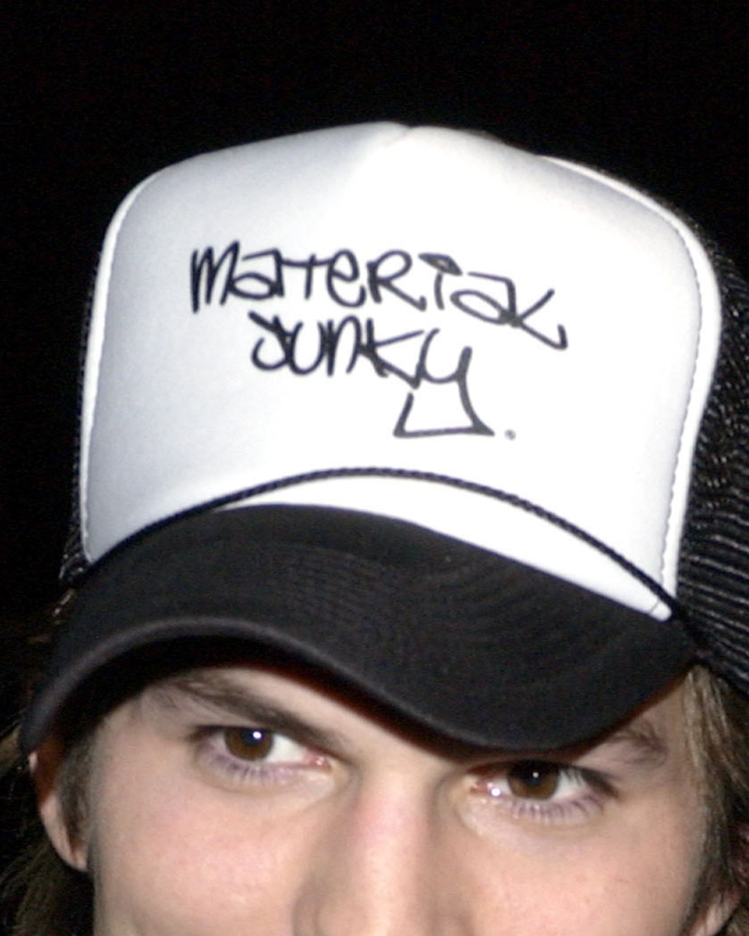 A close-up of Ashton Kutcher's "Material Junky" trucker hat