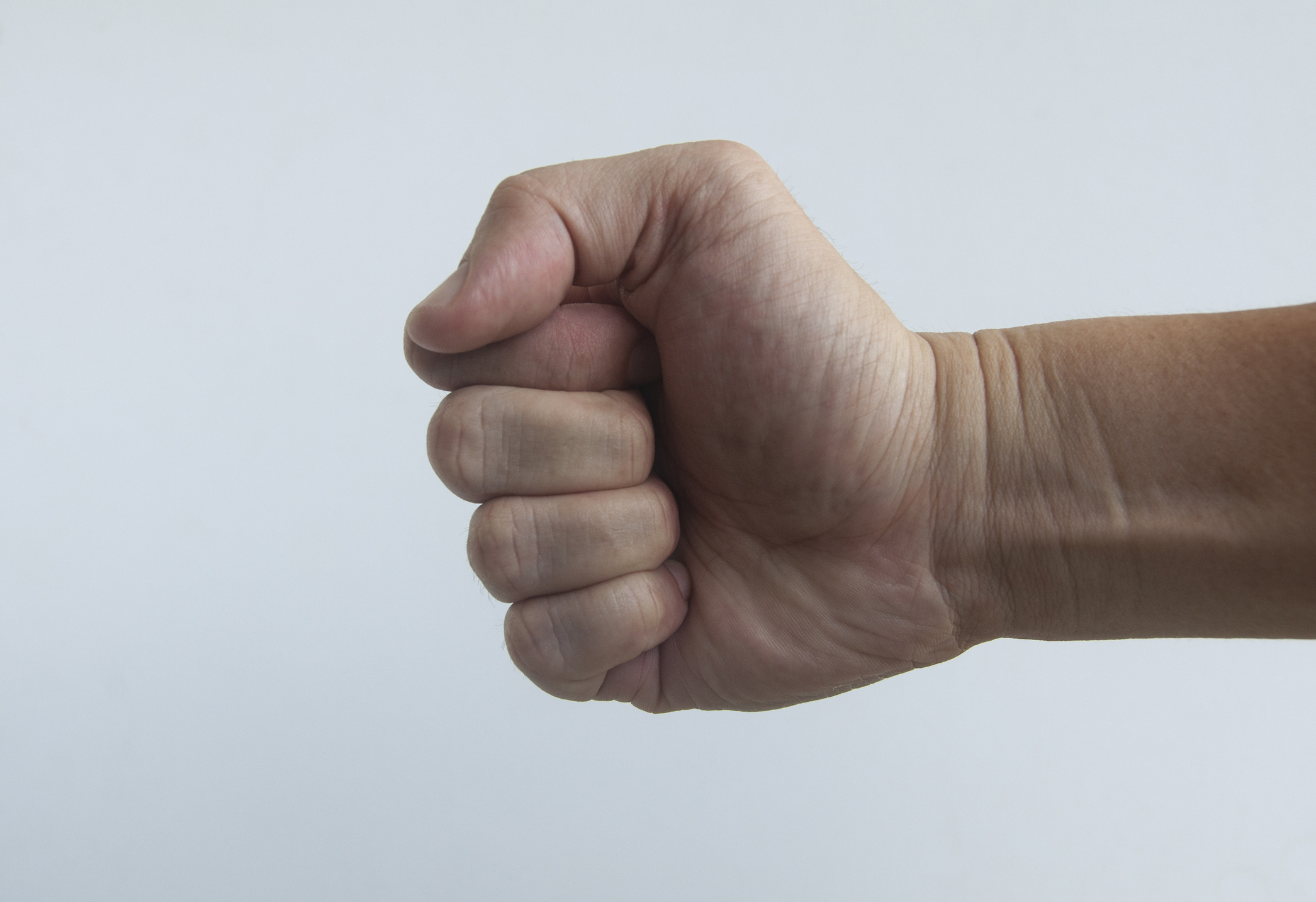 A close-up of a person's clenched fist against a plain background