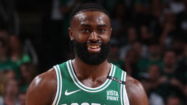 Jaylen Brown, wearing a green basketball jersey with white lettering, smiles during a game