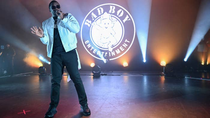 Sean &quot;Diddy&quot; Combs performs on stage, wearing a casual jacket and sunglasses, with a &quot;Bad Boy Entertainment&quot; logo projected behind him