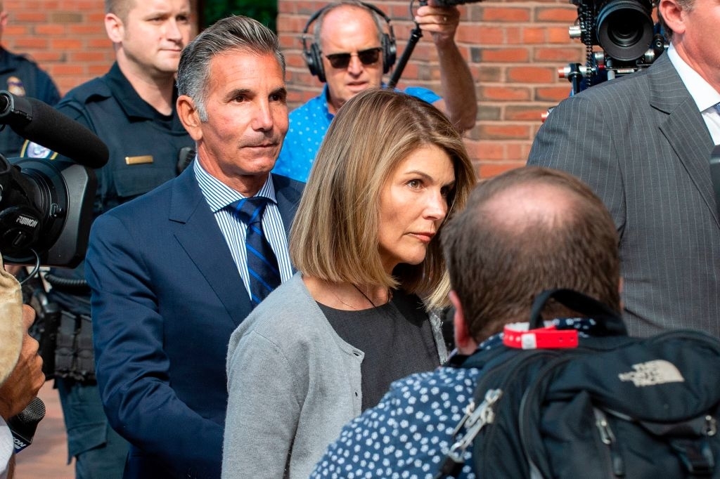 Lori Loughlin and Mossimo Giannulli walk into a building surrounded by press and security