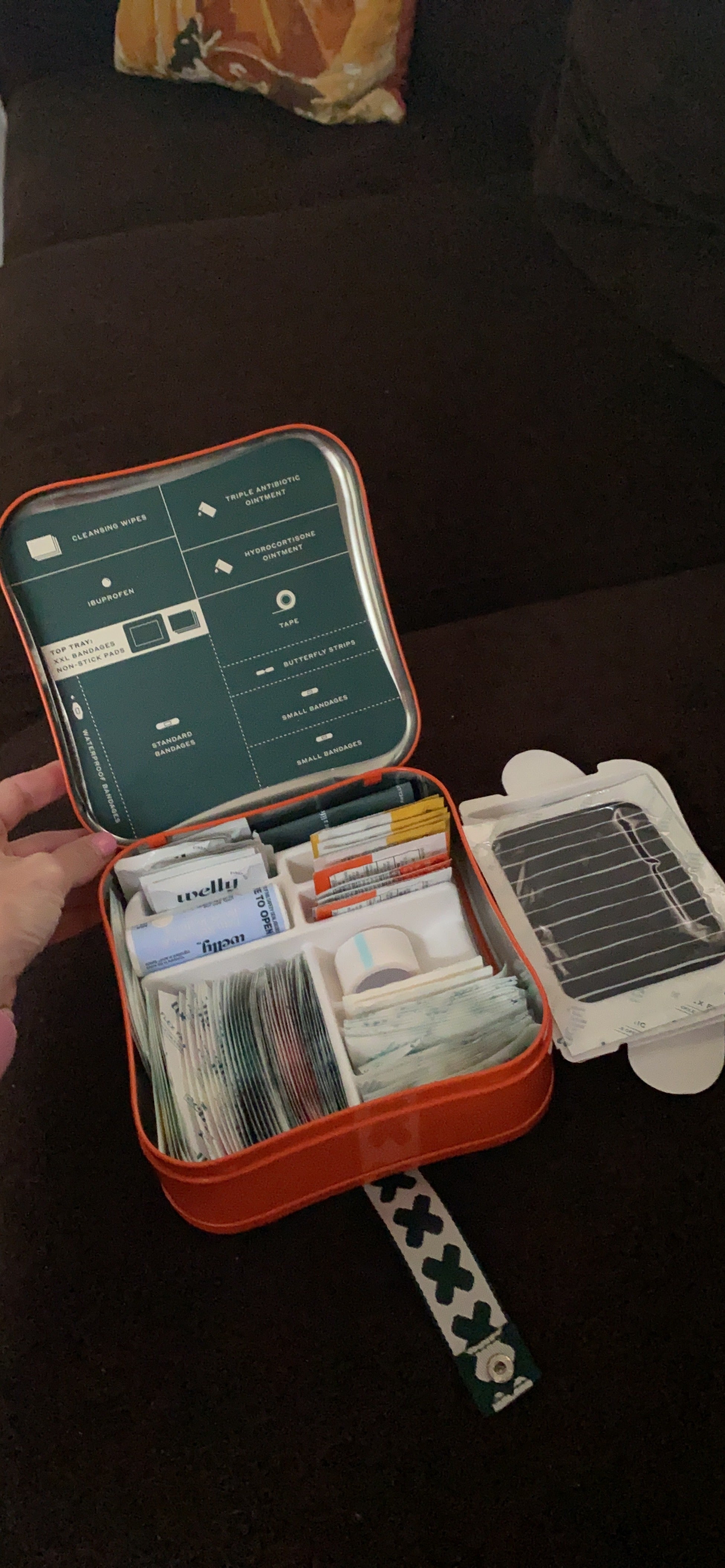 First assistance  kit with unfastened  lid showing organized aesculapian  supplies including bandages, antiseptic wipes, and assorted  medications