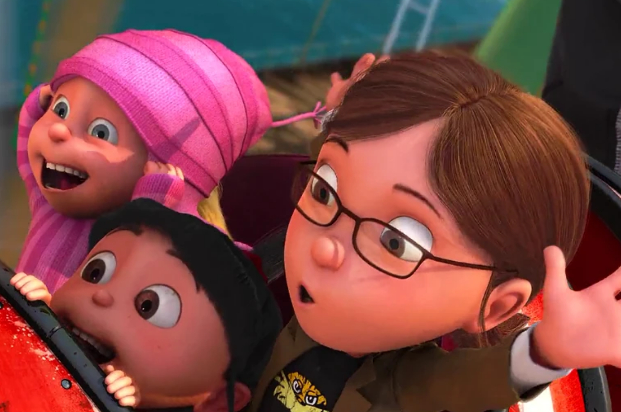 Margo, Edith, and Agnes from "Despicable Me" are excitedly riding a carnival ride. Margo, wearing glasses and a jacket, has her arms up in joy