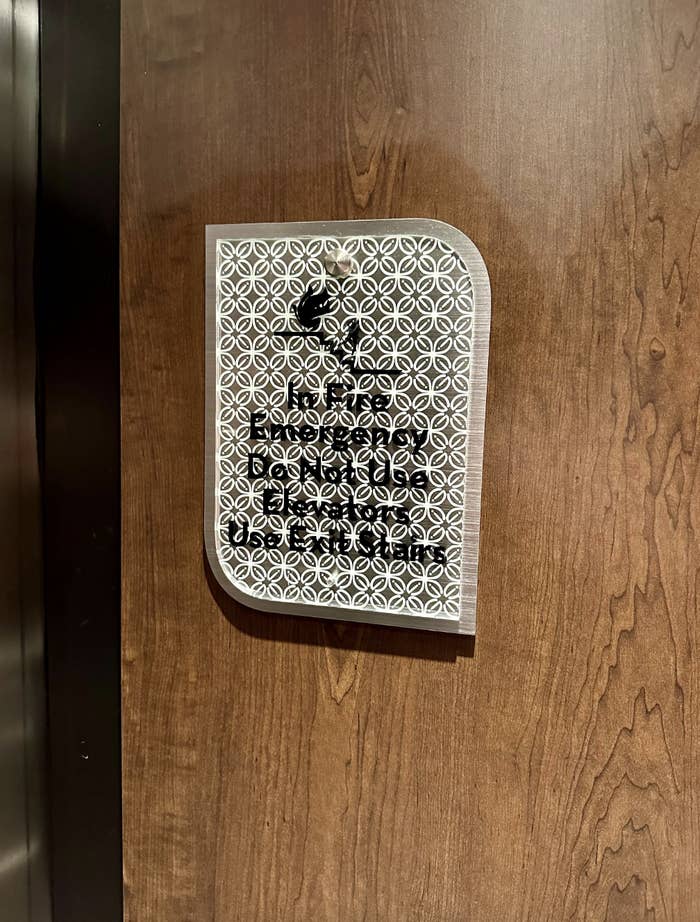 Sign on a wooden door with intricate circular patterns and readable text: "Please do not disturb, I'm busy making a soft and cozy spot for you!"