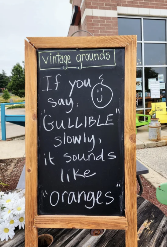 Chalkboard outside Vintage Grounds coffee shop reads: "If you say 'GULLIBLE' slowly, it sounds like 'oranges'" with a smiley face