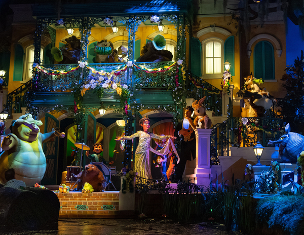 Tiana from "The Princess and the Frog" sings on a decorated balcony while animal characters play music and dance during a festive nighttime scene