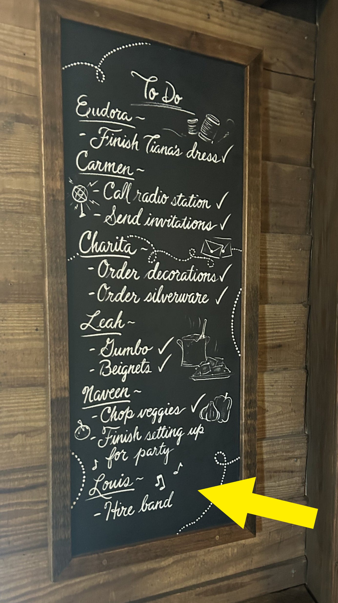 A wooden board with a "To Do" list featuring names and tasks such as: finish Tiana's dress, call radio station, send invitations, order decorations, make gumbo