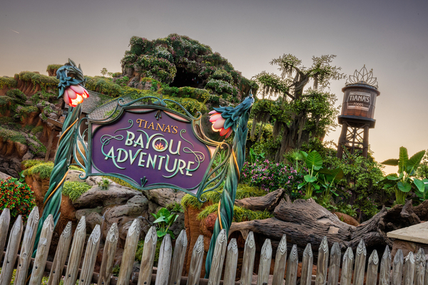 Entrance sign to Tiana's Bayou Adventure with lush greenery and a water tower in the background