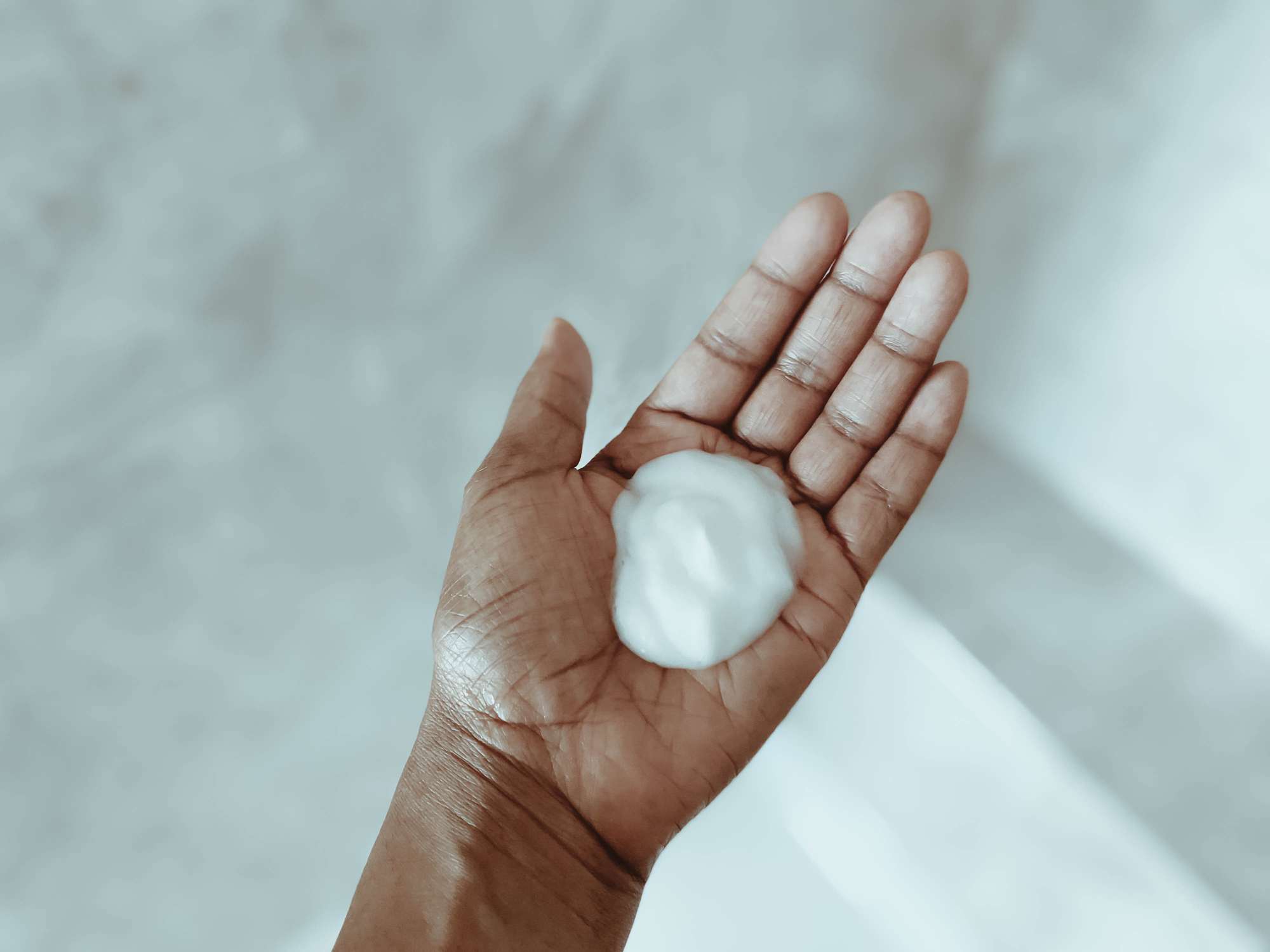 A hand with an open palm holding a small amount of white foamy substance