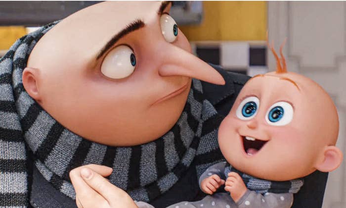 Gru sosteniendo a Bebé en sus brazos, ambos personajes de la película "Mi villano favorito". Gru lleva una bufanda de rayas. Bebé sonríe ampliamente