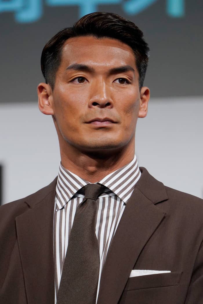 男性がスーツを着てポーズを取っている。