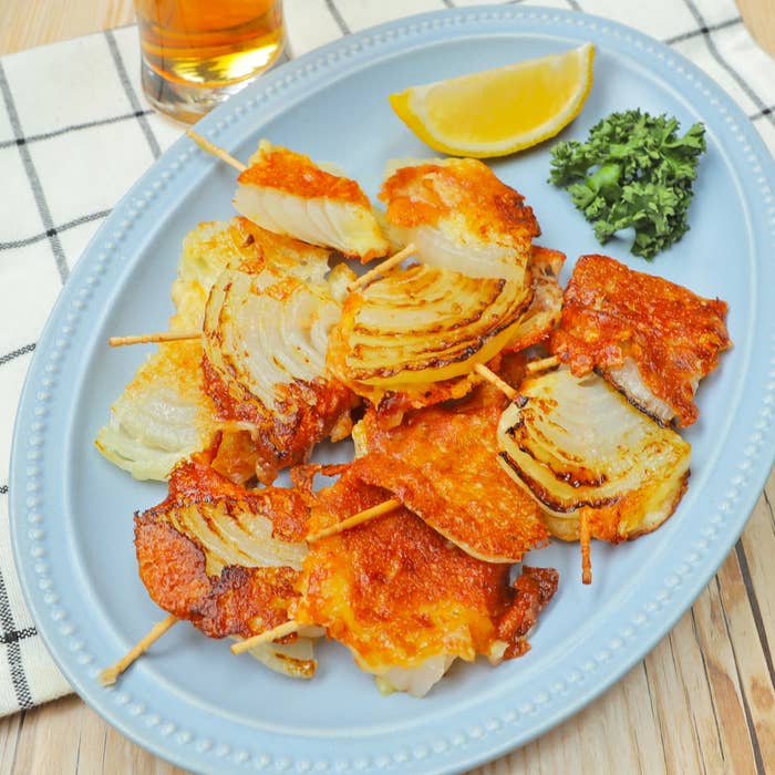 皿に盛られた串焼きの玉ねぎ料理とレモン、パセリが添えられています。