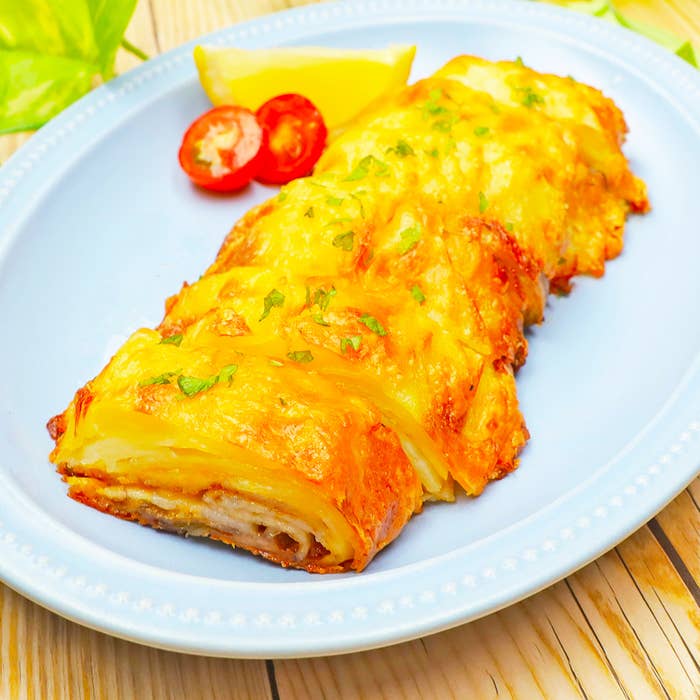 皿に盛られたおいしそうな料理。パセリで飾られたチーズが溶けている。食事シーン。