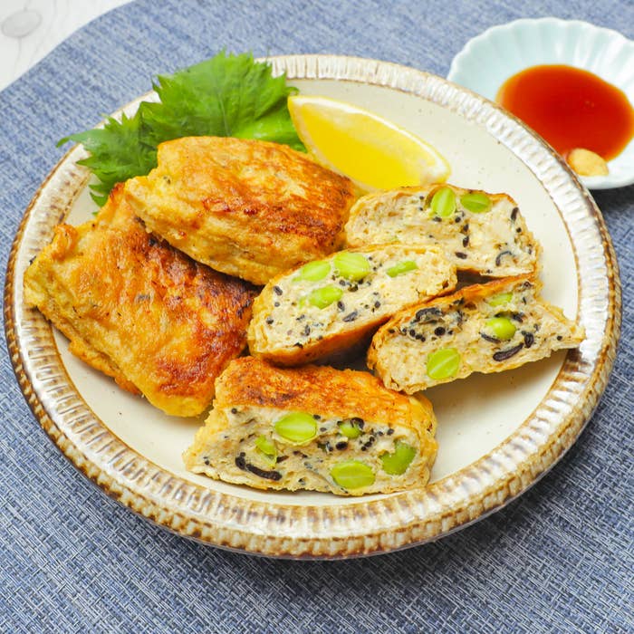 皿に盛られた野菜と豆腐を使った揚げ物料理。隣にはレモンのくし切りとソースがある。