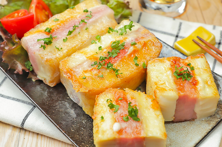 食事用プレートに並べられたベーコンとチーズを使った焼き料理とグラスに入った飲み物。