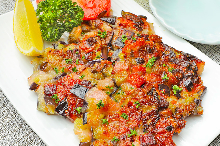 皿の上に揚げ茄子とトマトの焼き物、レモン、パセリが盛り付けられています。