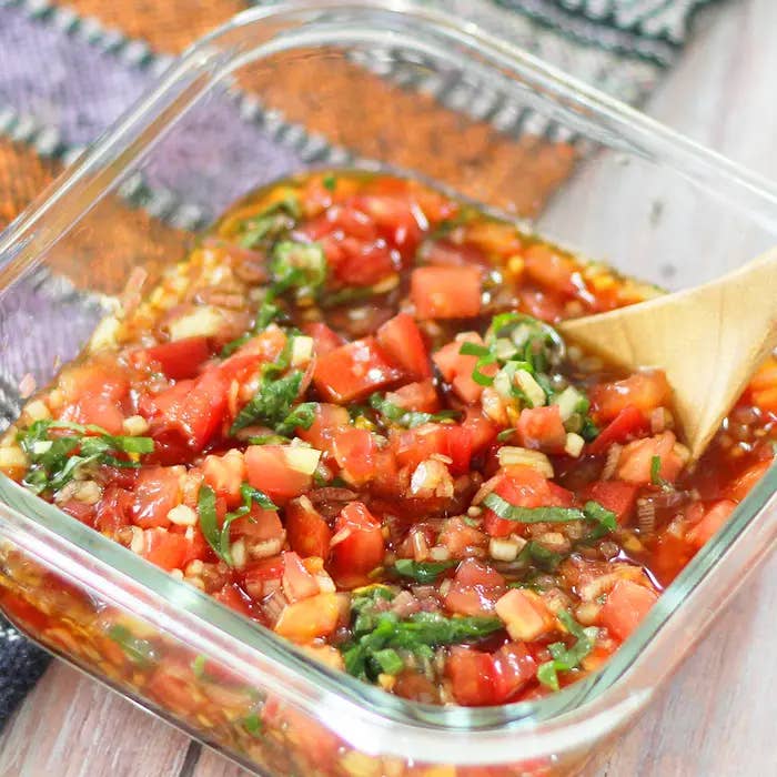 ガラス製容器に盛り付けられた新鮮なトマトサルサ、木製のスプーンが見える。