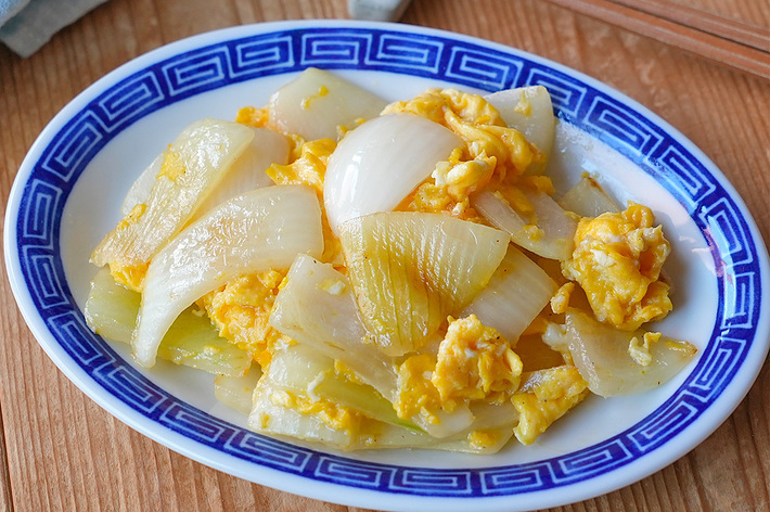 プレートに盛られた炒めた白菜と卵の料理。隣に箸とグラスが置かれている。