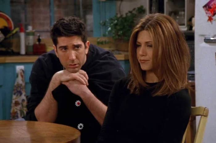 David Schwimmer and Jennifer Aniston in a kitchen scene from Friends, with Schwimmer's character looking concerned and Aniston's character appearing contemplative