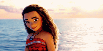 Moana, the animated character from the Disney movie "Moana," is standing by the ocean, wearing a red patterned dress and a shell necklace.