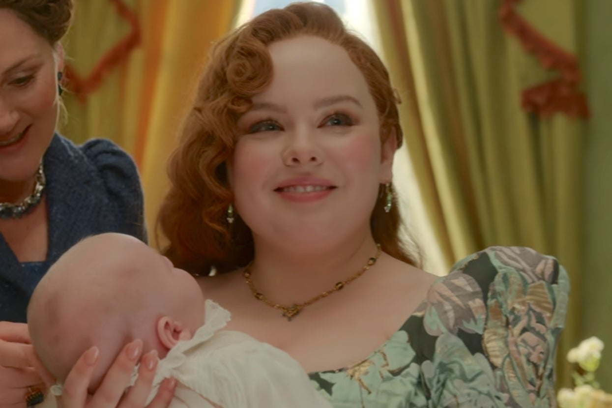 Penelope from Bridgerton smiling and holding a baby