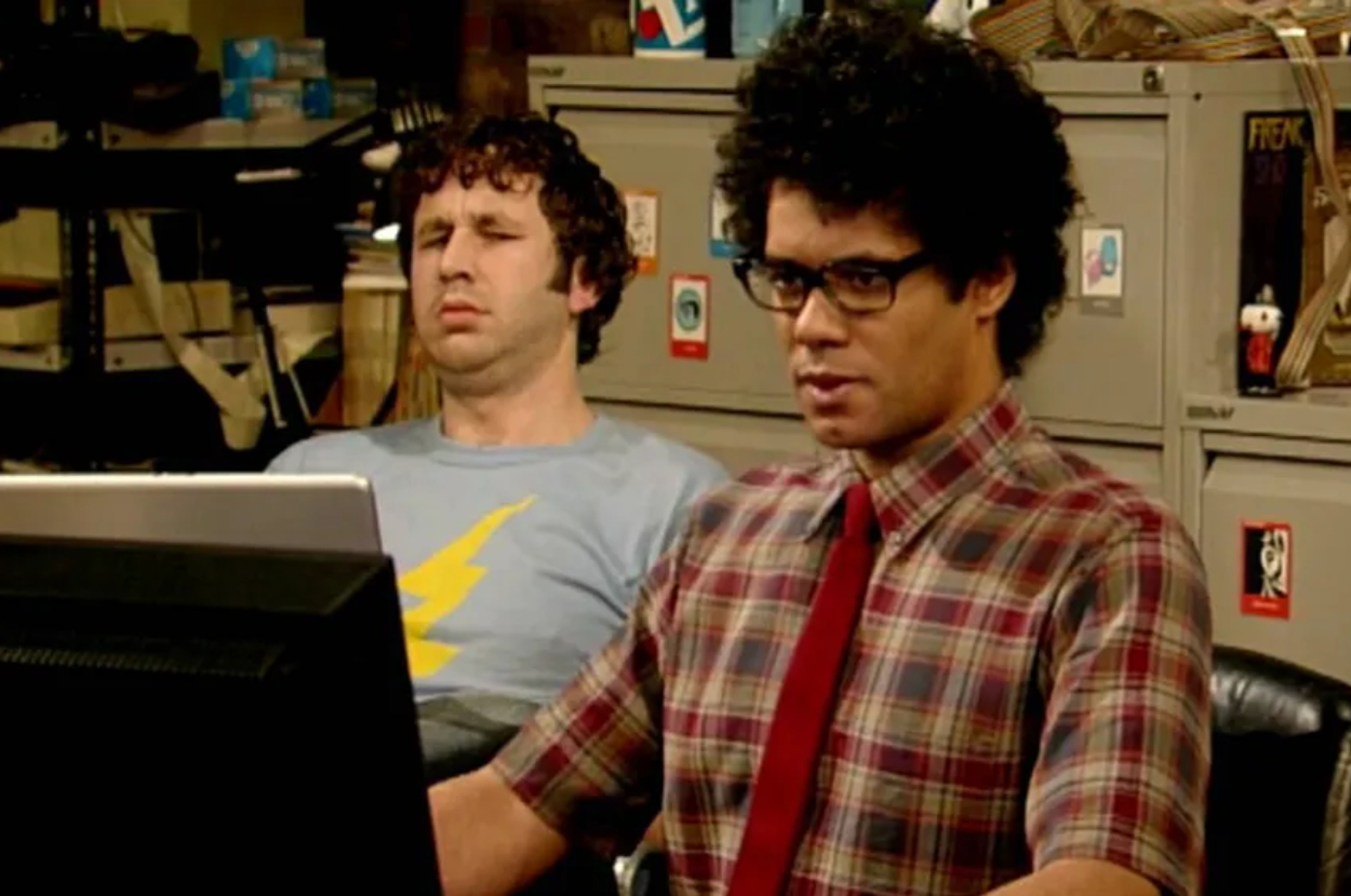 Chris O'Dowd in a blue shirt with a yellow lightning bolt and Richard Ayoade in a plaid shirt with a red tie appearing on the set of The IT Crowd