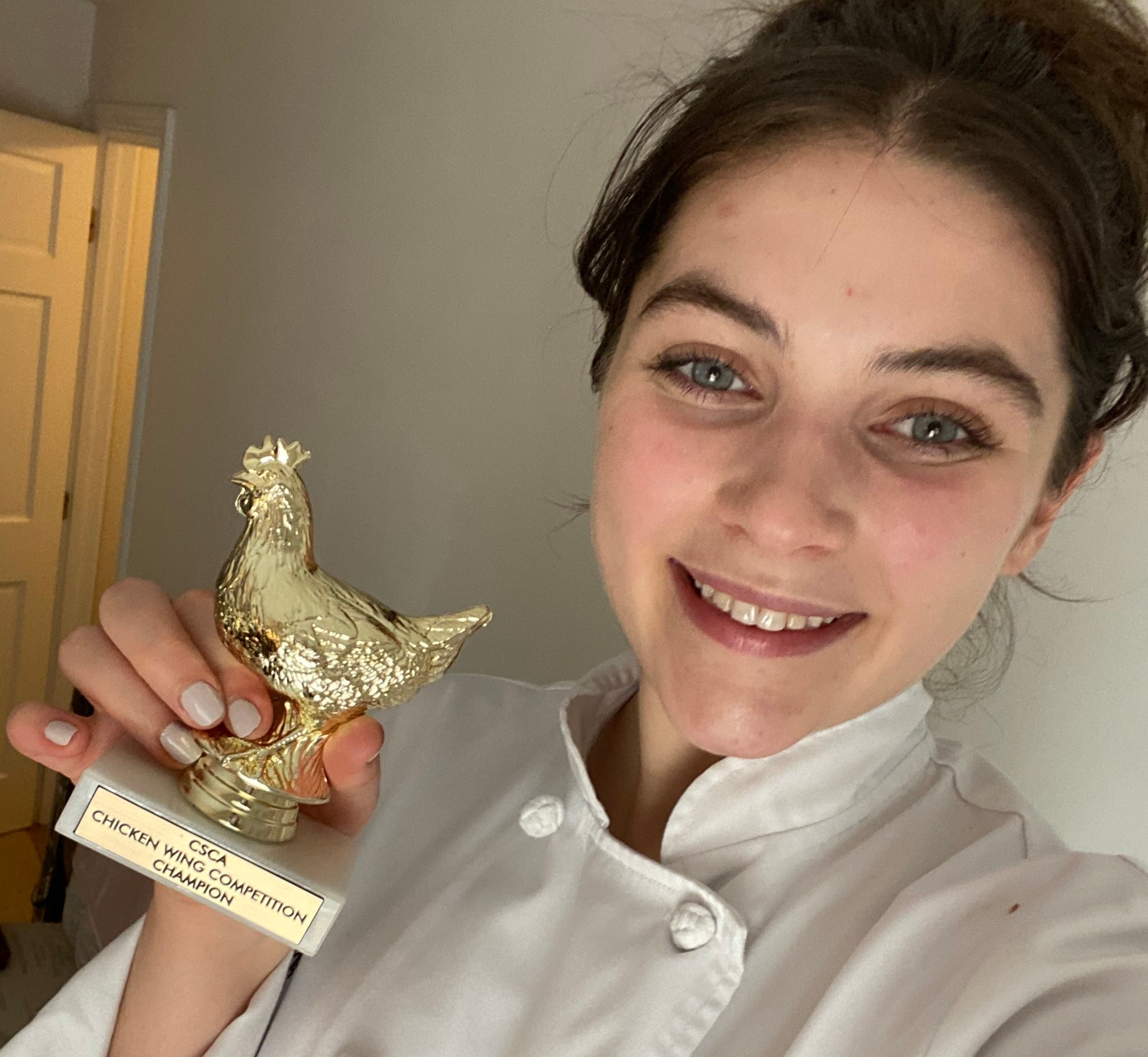 Meg Sullivan in a Chef coat holding a golden, chicken-shaped trophy