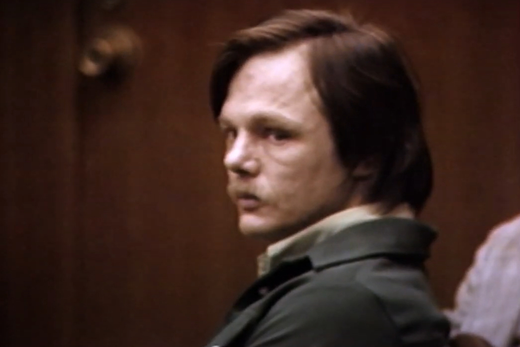 Lawrence Bittaker with short hair wears a jacket and looks to the side while seated indoors. The background is blurred.