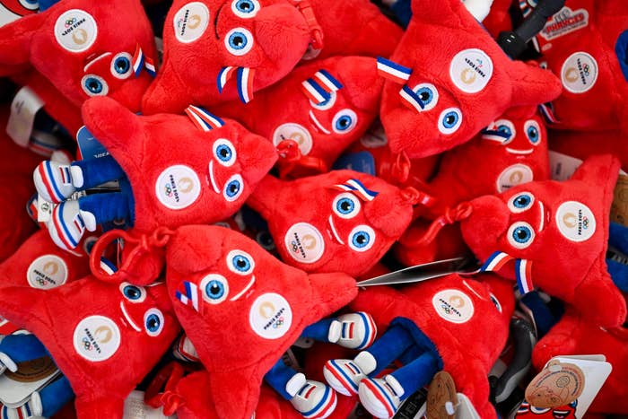 A pile of red plush mascots with wide eyes and tricolor stripes, representing the 2024 Paris Olympics