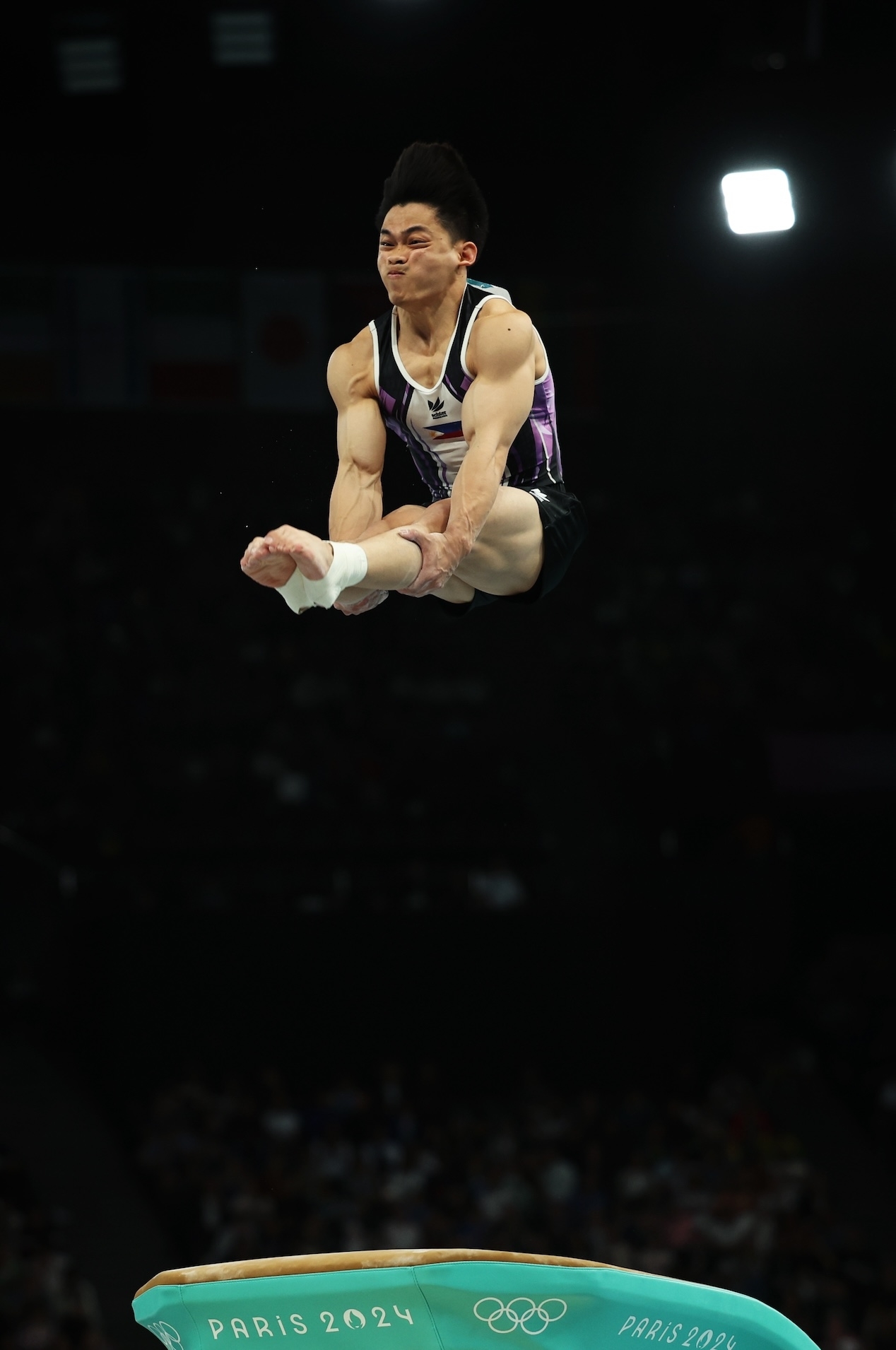 Gymnast performing a high tuck jump on the vault at the Paris 2024 Olympics
