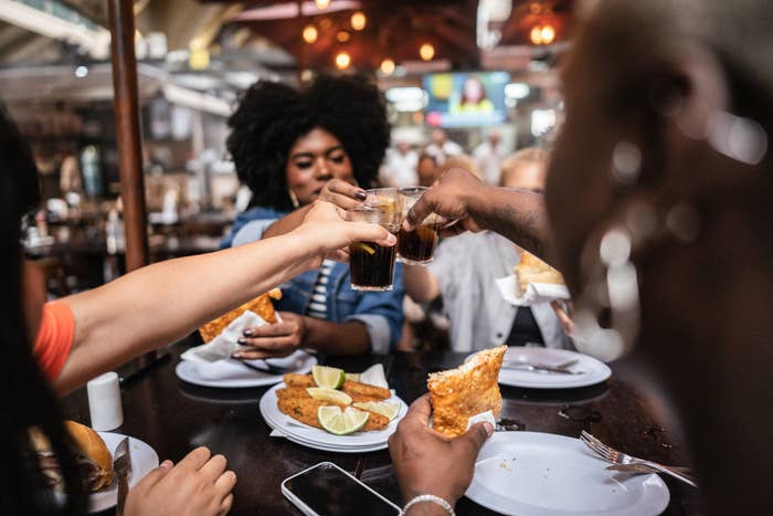 People at a restaurant toasting with drinks over a meal, focusing on camaraderie and dining out