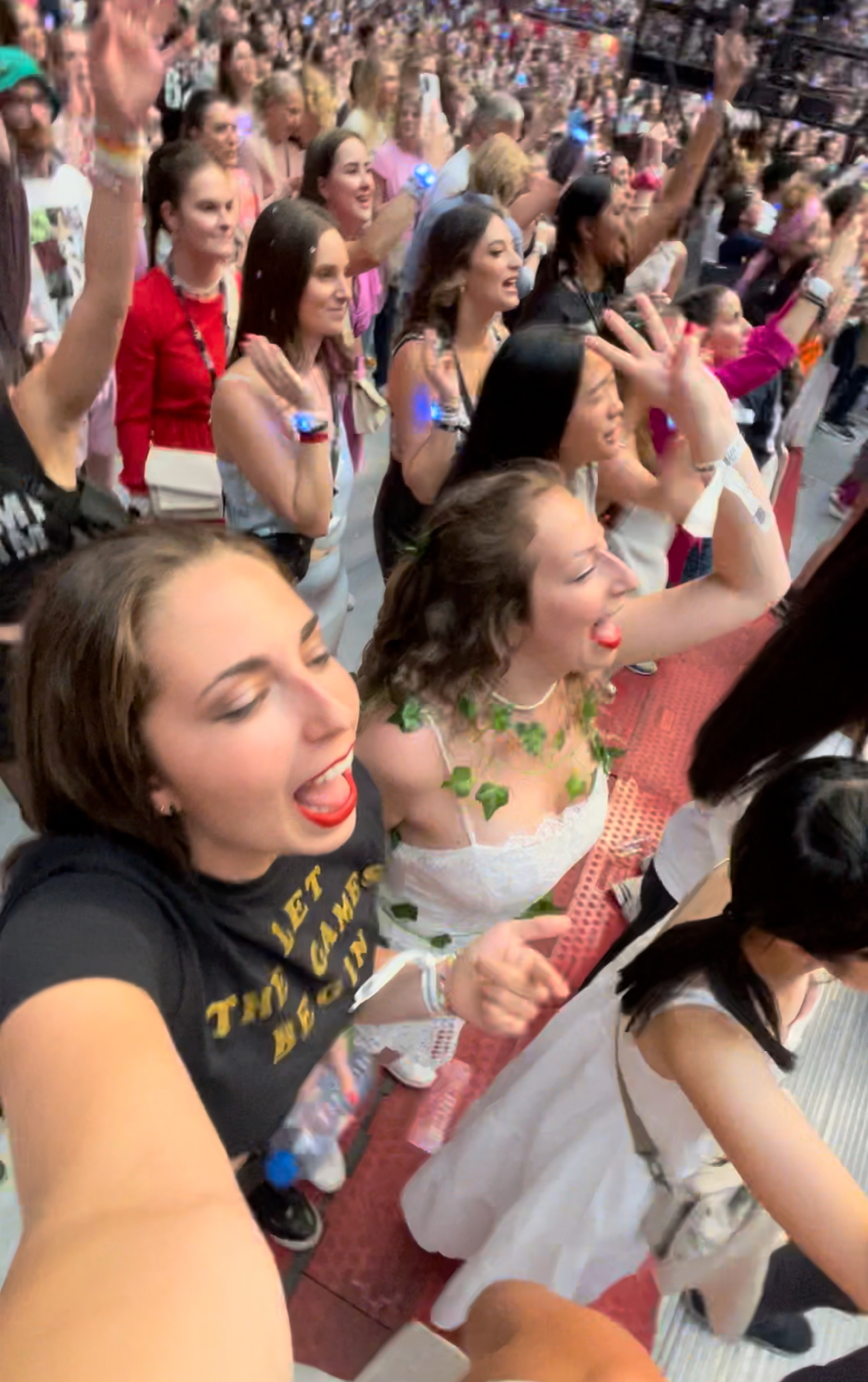 Concertgoers at a music event cheer, sing, and enjoy the performance, expressing excitement and enthusiasm in a packed venue