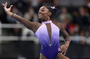 Simone Biles performs a gymnastics routine, wearing a sparkling, long-sleeve leotard