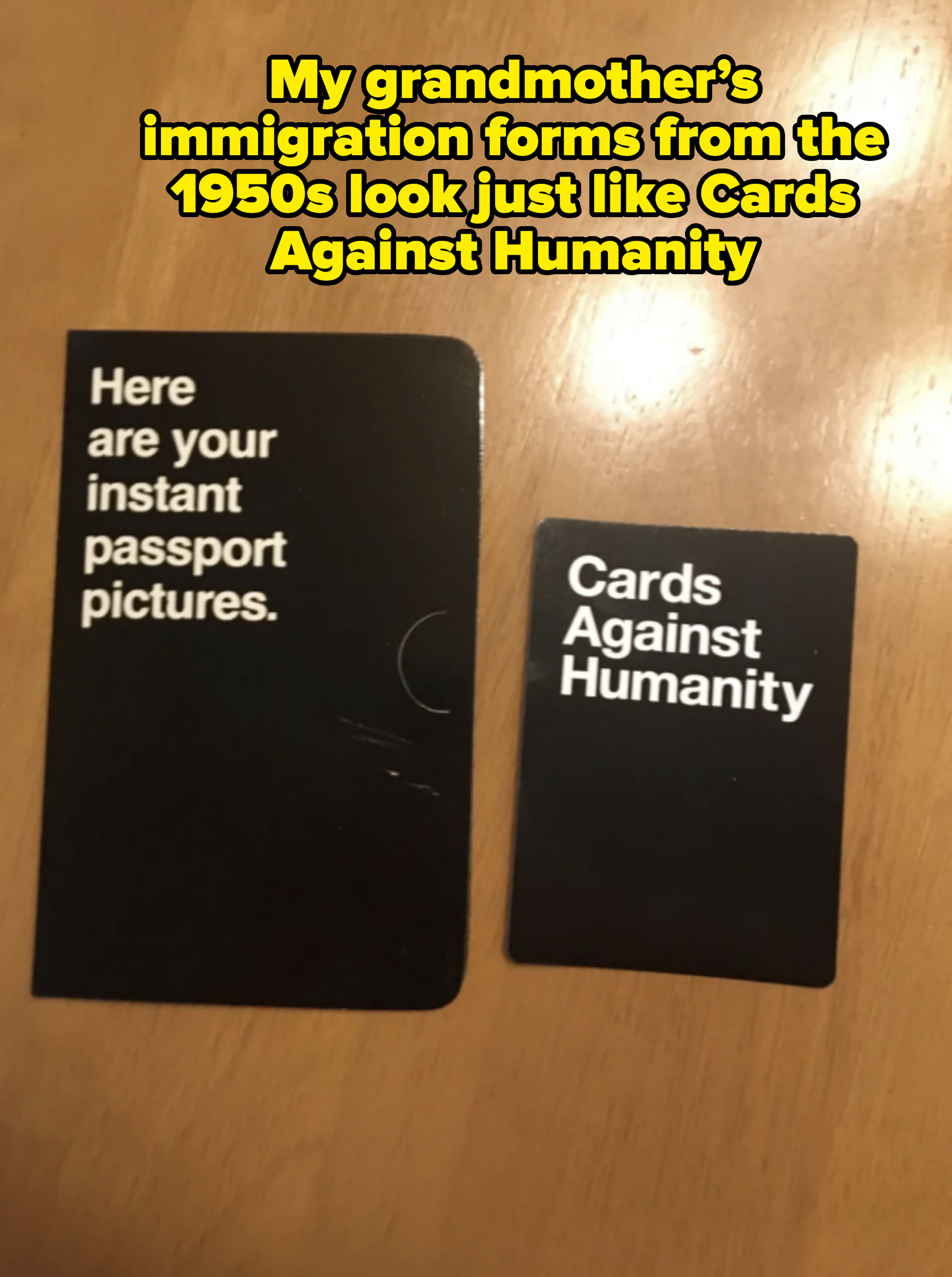 Two black cards on a wooden surface. One reads, "Here are your instant passport pictures." and the other reads, "Cards Against Humanity."