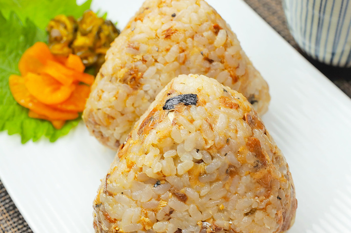 おにぎり2つが皿に盛られており、付け合わせに漬物があります。