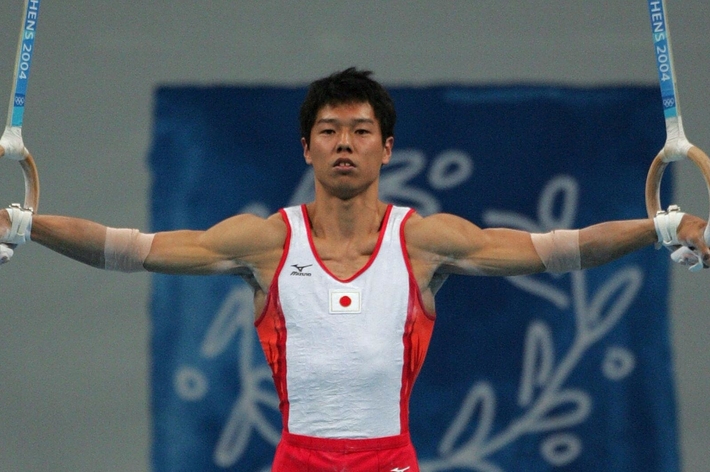 アテネ2004オリンピックで吊り輪演技中の体操選手。