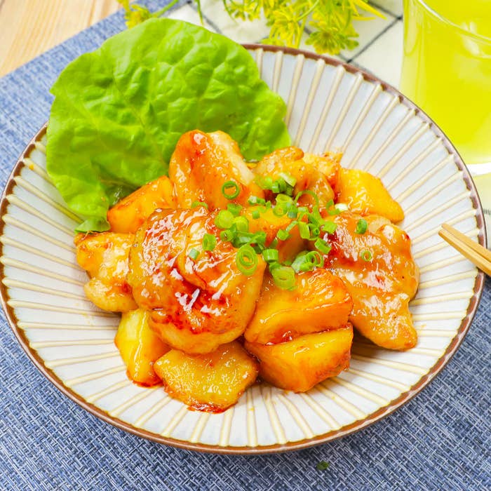 皿に盛られた甘辛いソースがかかった鶏肉料理。レタスの葉と青ネギが添えられている。