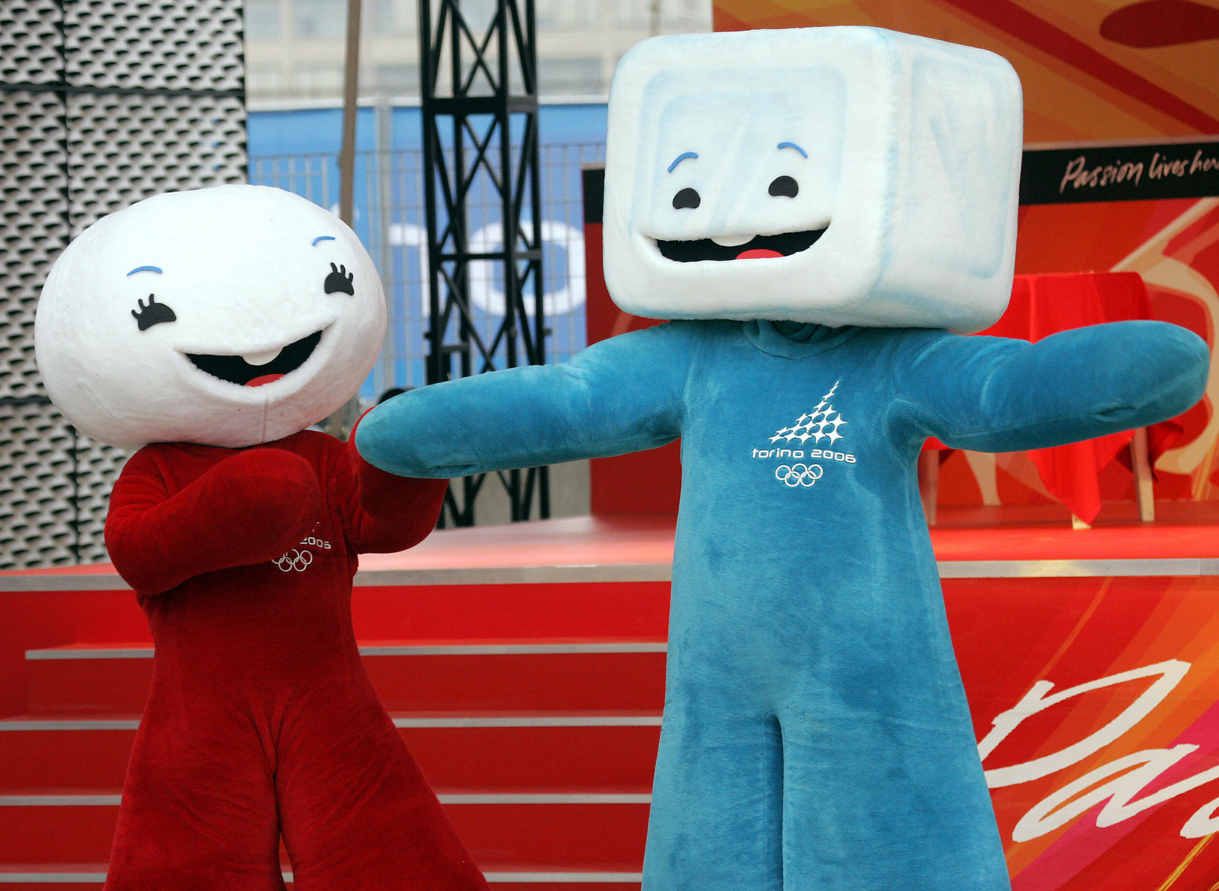 Two mascots from the 2006 Winter Olympics in costume, Neve (left, snowball-like) and Gliz (right, ice cube-like), standing side by side, smiling