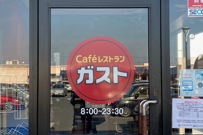カフェレストラン「ガスト」の入口ドア。営業時間は8:00から23:30と表示されています。
